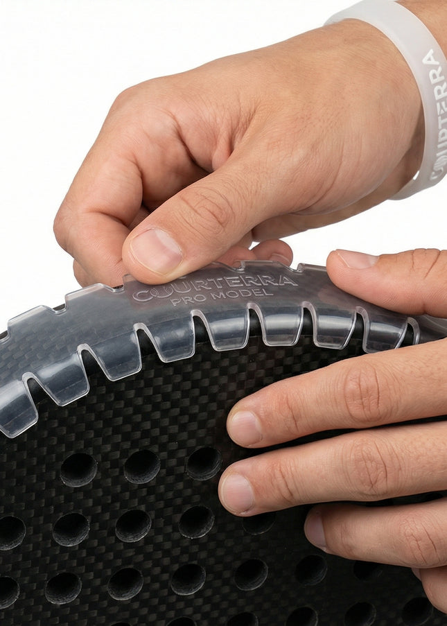 Close-up of athlete hands applying Courterra sawtooth edge protector to a carbon fiber padel racket showing wrinkle-free installation.