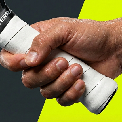 Close-up of a single Courterra White X-PRO overgrip roll showing the 0.6mm thickness and smooth tacky PU texture.